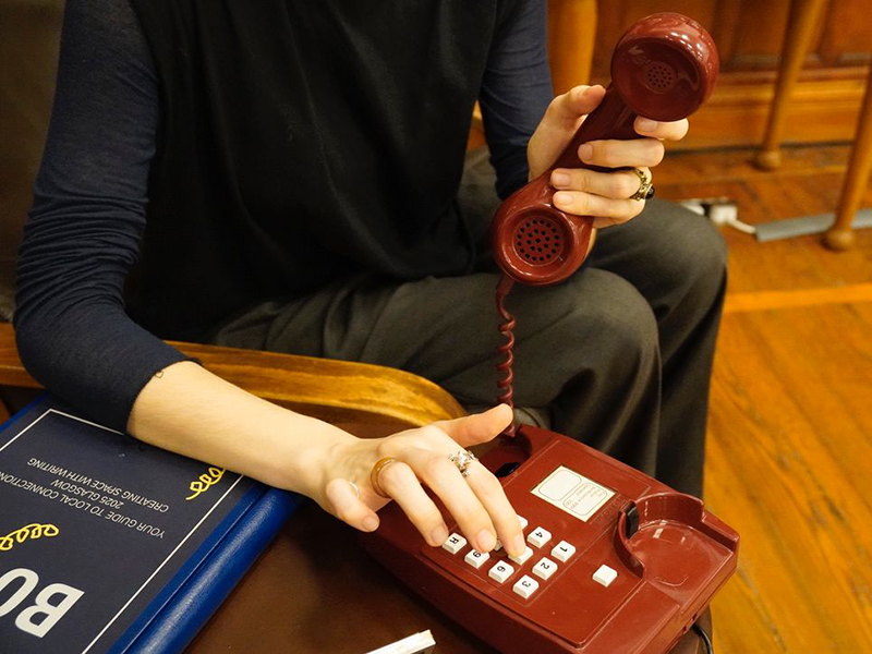 A hand pressing buttons on the push button phone.